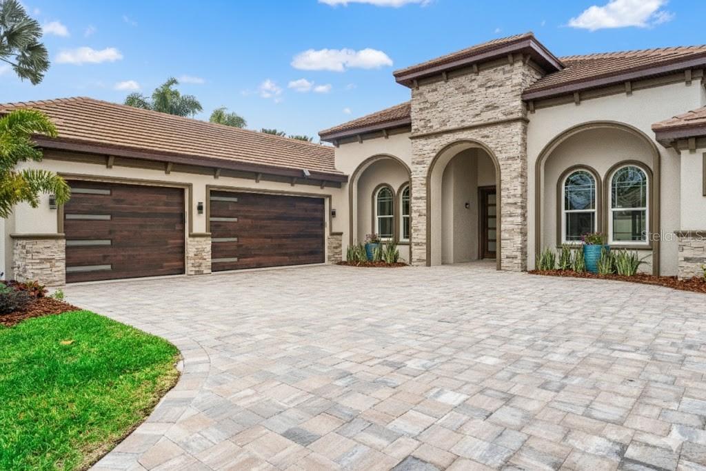 A single-story house with a stone-accented entrance, arched windows, and a paved driveway at dusk — 10700 PONTOFINO CIRCLE, TRINITY, FL