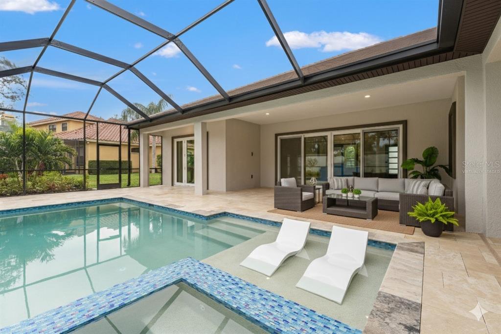 A screened-in patio features a swimming pool with a spa and a tiled water feature — 10700 PONTOFINO CIRCLE, TRINITY, FL