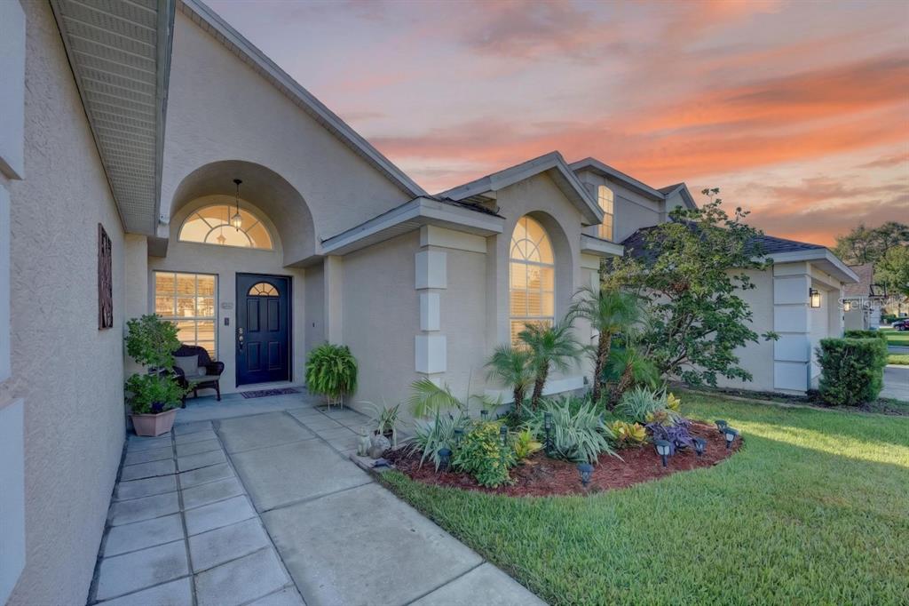 A beige house exterior features a dark front door, arched windows, and a landscaped garden — 437 RANDON TERRACE, LAKE MARY, FL