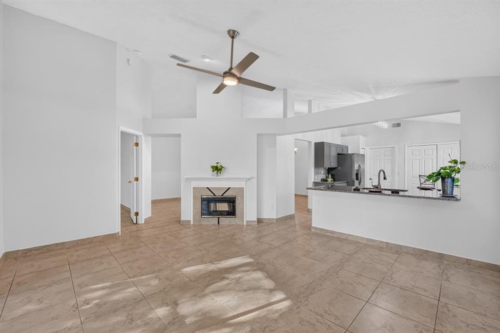 A living room with tile flooring, a fireplace, and an open kitchen with a breakfast bar — 437 RANDON TERRACE, LAKE MARY, FL