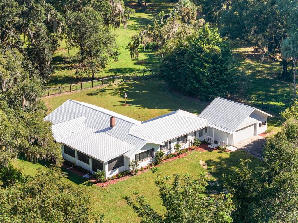 An aerial view of a white house with a metal roof and attached garage — 17067 NW GAINESVILLE ROAD, REDDICK, FL