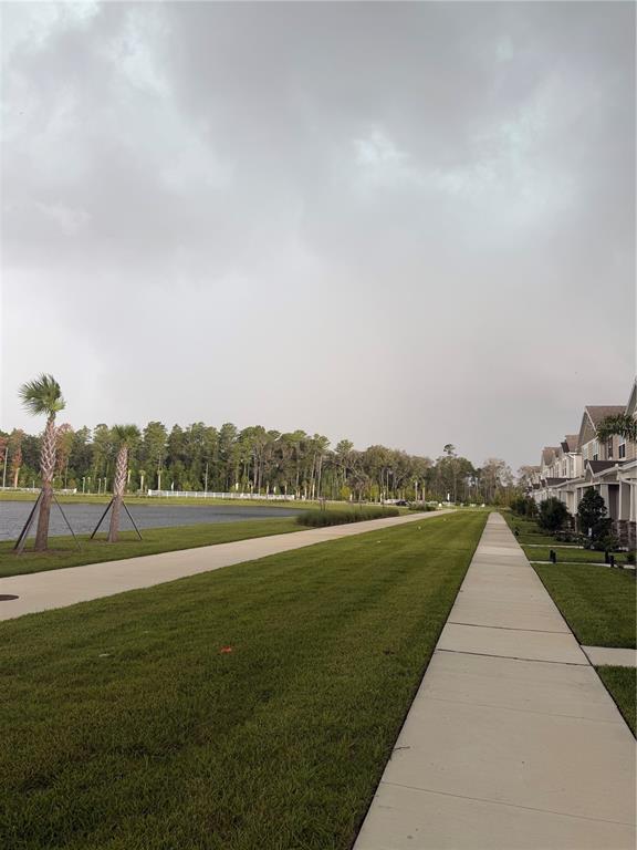 A sidewalk runs between a grassy lawn and a row of townhouses beside a pond — 9972 RED CANOE ALLEY, ORLANDO, FL