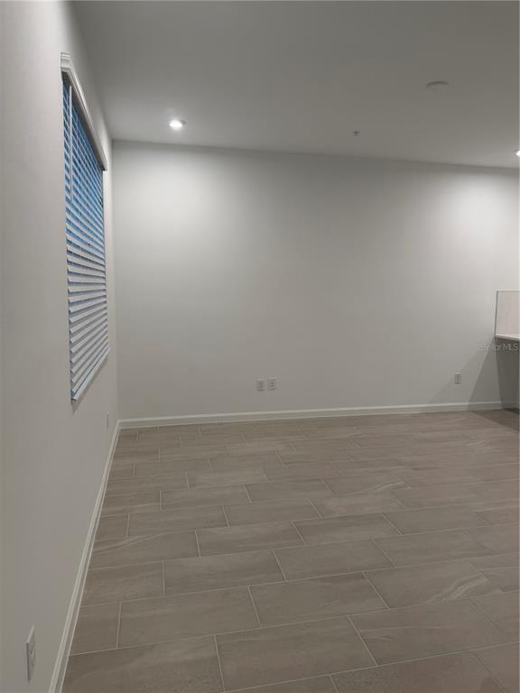 An empty room with light-colored tile flooring, white walls, and a window with blue blinds — 9972 RED CANOE ALLEY, ORLANDO, FL