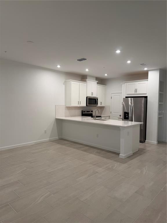 A kitchen features white cabinets, stainless steel appliances, a breakfast bar, and light tile flooring — 9972 RED CANOE ALLEY, ORLANDO, FL