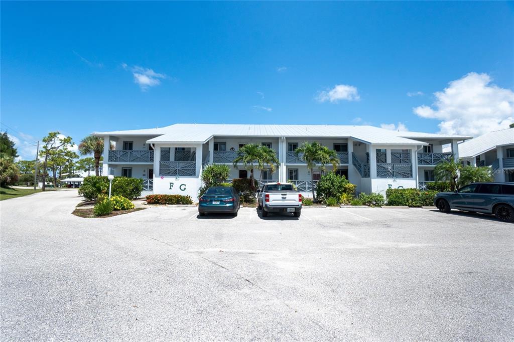 A two-story apartment building with a white exterior and a parking lot in front — 6800 PLACIDA ROAD UNIT 1007, ENGLEWOOD, FL