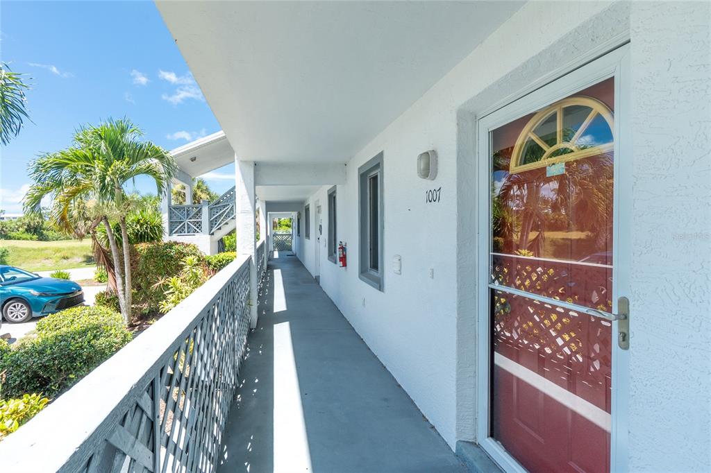 An exterior walkway leads to a red front door with a decorative arched window — 6800 PLACIDA ROAD UNIT 1007, ENGLEWOOD, FL