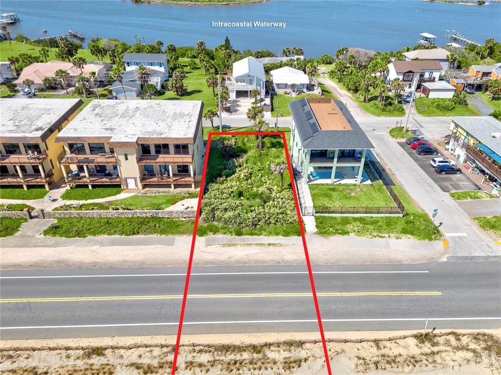 An aerial view shows a vacant, rectangular lot situated between two buildings near a waterway — 21XX N OCEAN SHORE BOULEVARD, FLAGLER BEACH, FL
