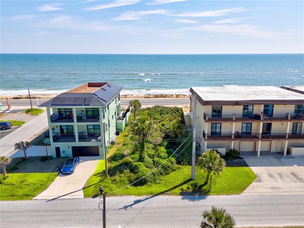 An aerial view shows two multi-story buildings separated by a vacant lot near the ocean — 21XX N OCEAN SHORE BOULEVARD, FLAGLER BEACH, FL