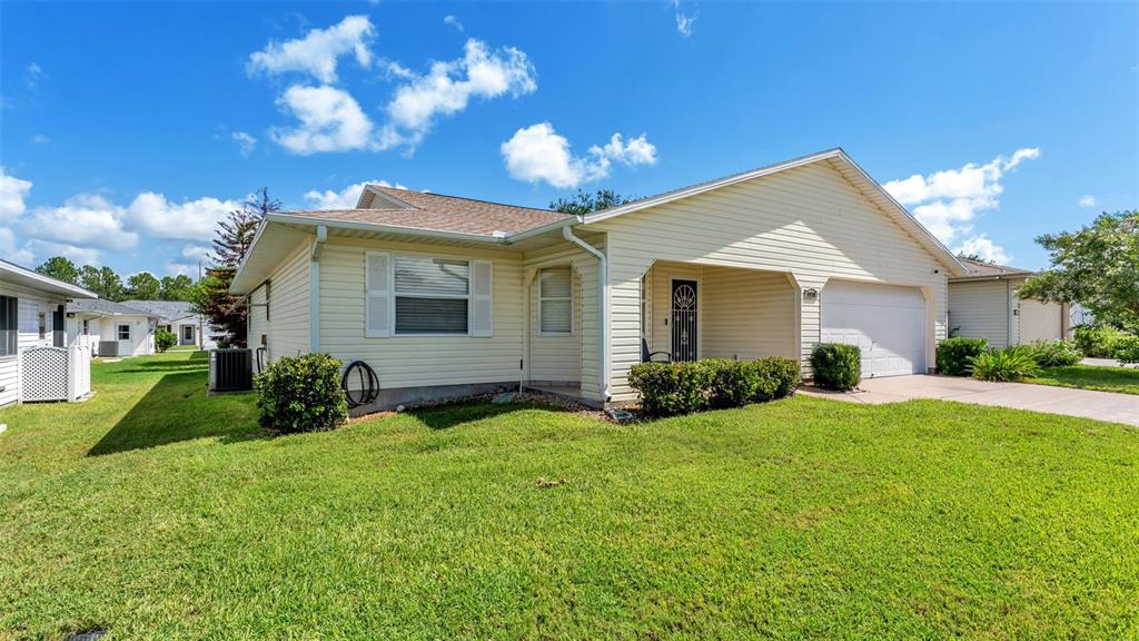 A single-story house with light yellow siding, a front-facing garage, and a green lawn — 2227 GRAND CYPRESS DRIVE, LAKELAND, FL