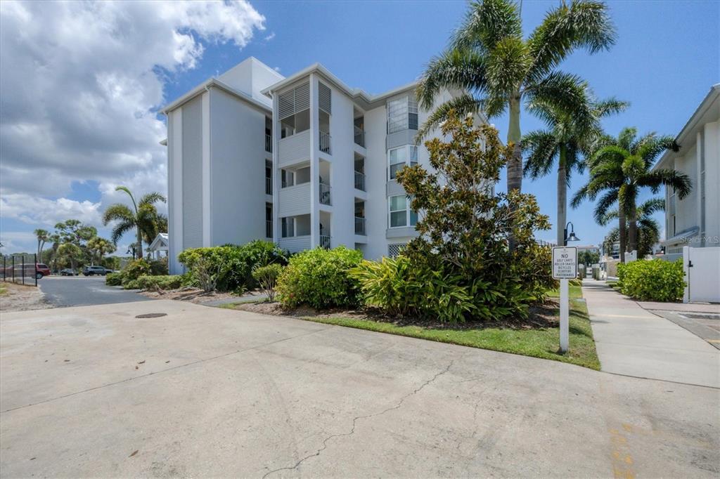 A multi-story white apartment building stands next to a paved path and palm trees — 7070 PLACIDA ROAD UNIT 1221, PLACIDA, FL