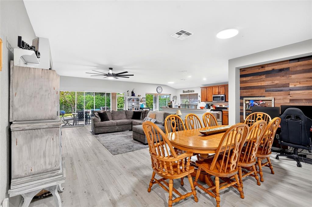 A living room features a wood-paneled accent wall, a large sectional sofa, and sliding doors — 4098 SW 47TH COURT, OCALA, FL