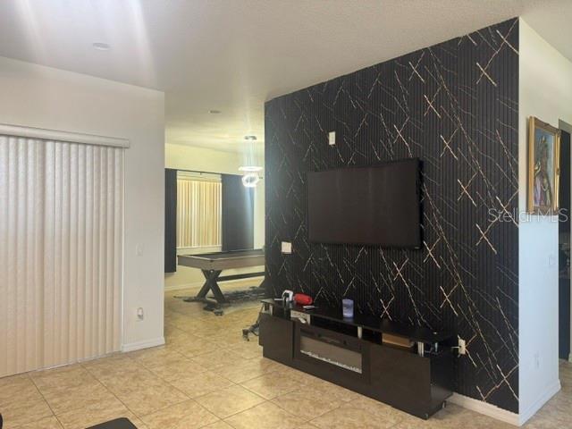 A living room features a black accent wall with gold detailing, a television, and tile flooring — 406 CINNAMON DRIVE, POINCIANA, FL