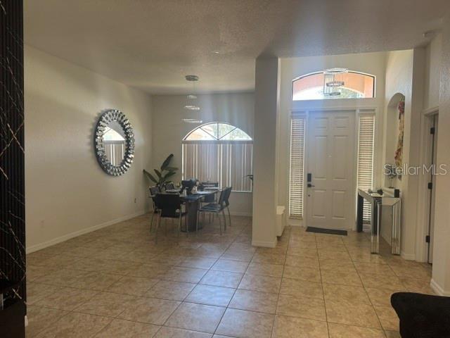 A dining area with tile floors and a large circular mirror sits near an entryway — 406 CINNAMON DRIVE, POINCIANA, FL