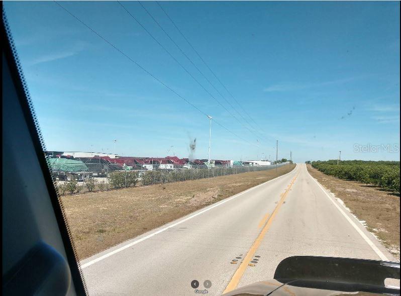 A view from a vehicle looking down a road beside a fenced industrial storage lot — N/A, FROSTPROOF, FL