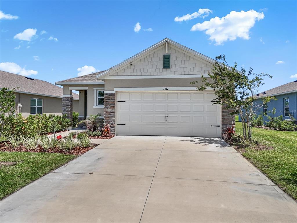 A single-story house features a two-car garage, stone accents, and a concrete driveway — 1337 CORK DRIVE, ORMOND BEACH, FL