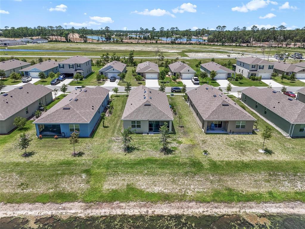 An aerial view shows a row of suburban houses with backyards facing a pond — 1337 CORK DRIVE, ORMOND BEACH, FL