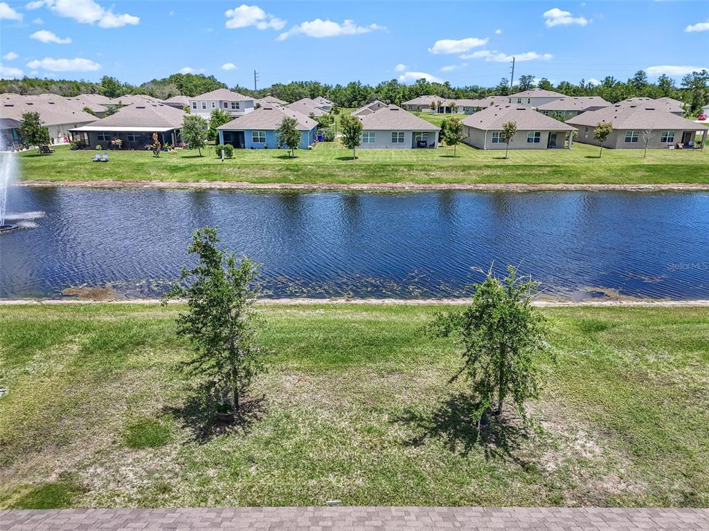 An elevated view of a backyard lawn, a pond with a fountain, and neighboring houses — 1337 CORK DRIVE, ORMOND BEACH, FL