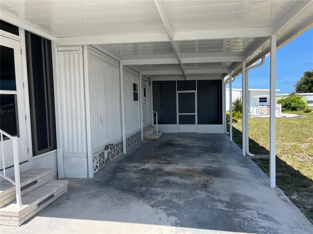 A covered concrete carport sits beside a mobile home with a screened-in porch area — 891 GRADO DRIVE, VENICE, FL