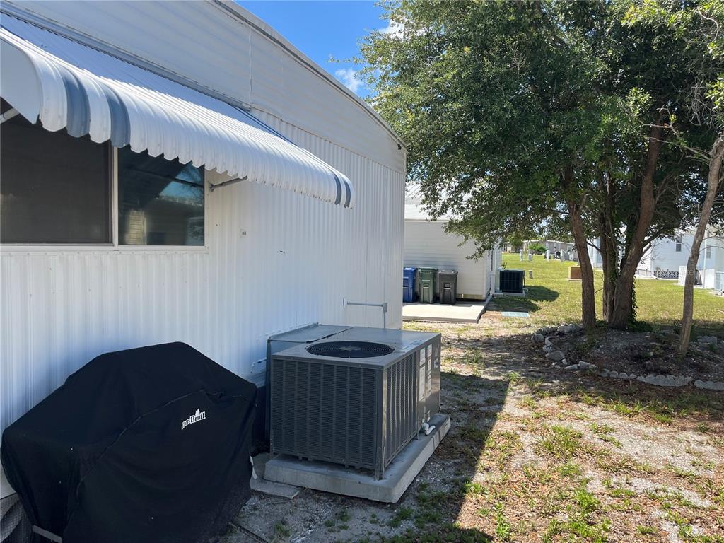 The exterior of a mobile home features a metal awning, air conditioning unit, and grill — 891 GRADO DRIVE, VENICE, FL