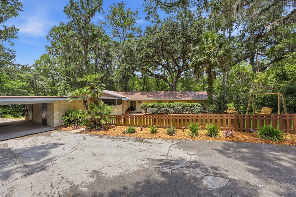 A single-story house with a carport, a wooden fence, and a swing set in the yard — 1732 NW 8TH AVENUE, GAINESVILLE, FL