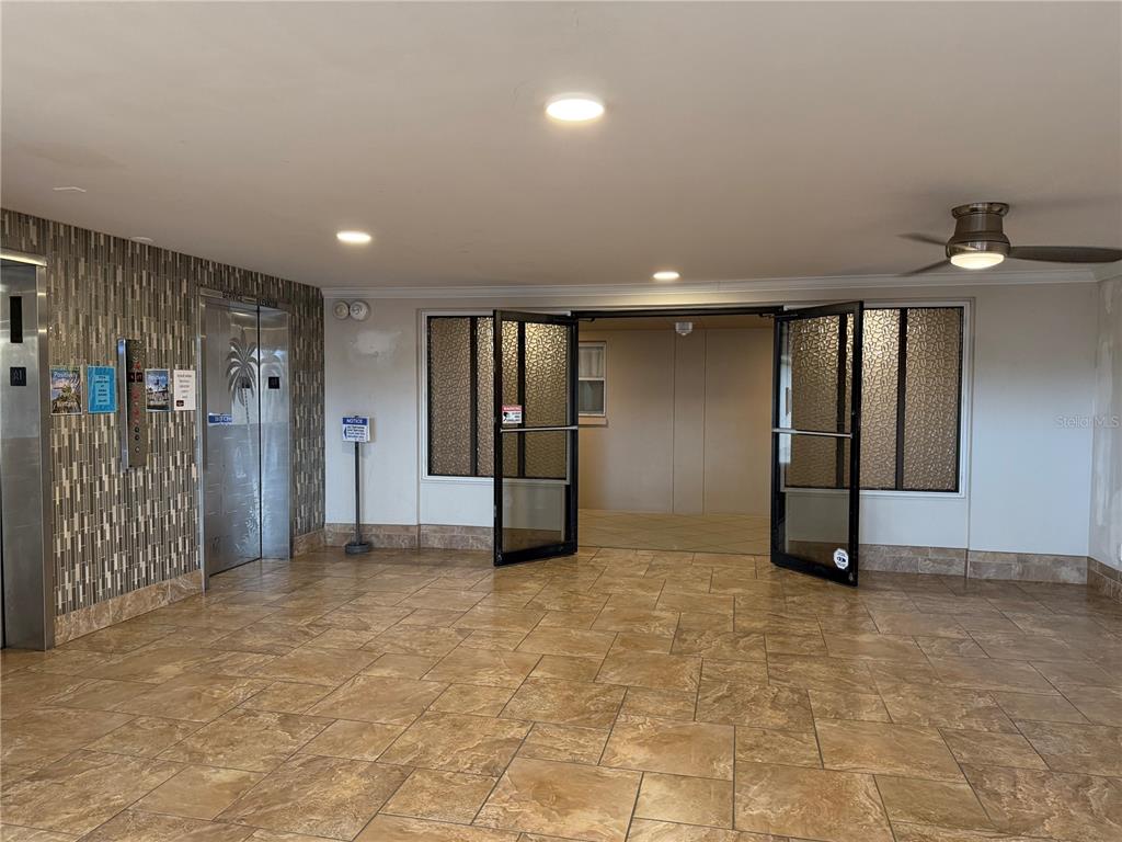 A tiled lobby features an elevator bank, glass double doors, and a ceiling fan — 5200 BRITTANY DRIVE S UNIT 609, ST PETERSBURG, FL