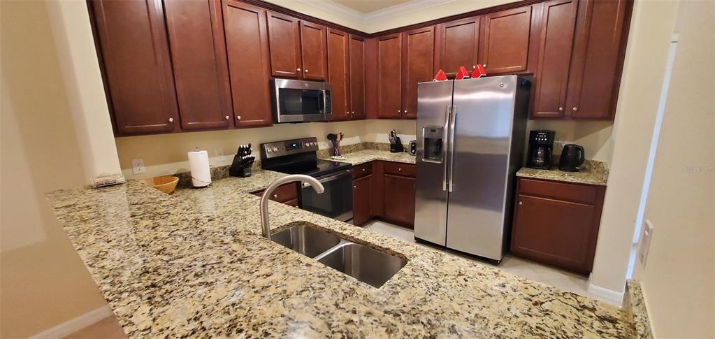A kitchen features dark wood cabinets, granite countertops, and stainless steel appliances — 20229 LAGENTE CIRCLE, VENICE, FL