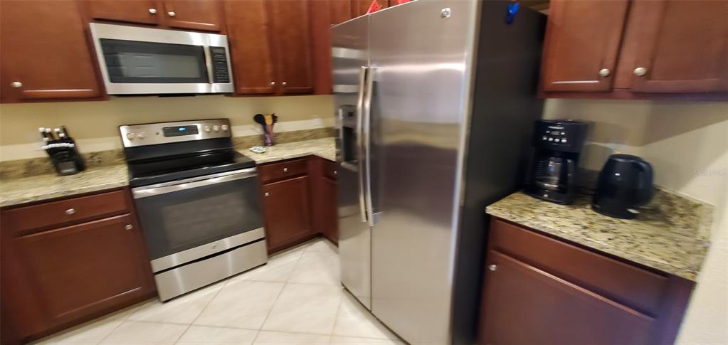 A kitchen features stainless steel appliances, dark wood cabinets, and granite countertops — 20229 LAGENTE CIRCLE, VENICE, FL