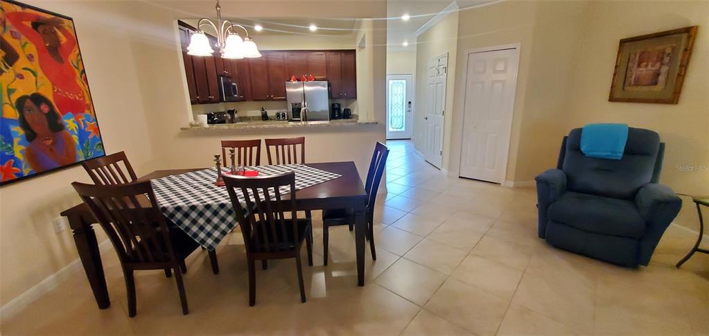 A dining area with a dark wood table and chairs sits adjacent to an open kitchen — 20229 LAGENTE CIRCLE, VENICE, FL