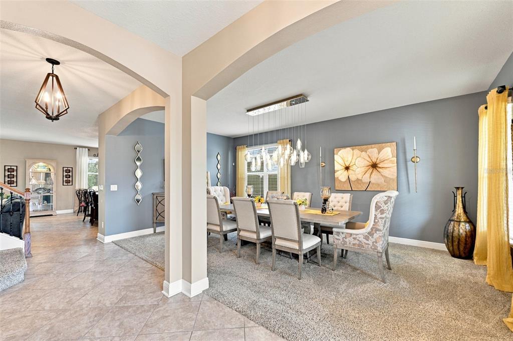 A dining room with a long table, upholstered chairs, and a modern glass pendant light — 11156 SPRING POINT CIRCLE, RIVERVIEW, FL