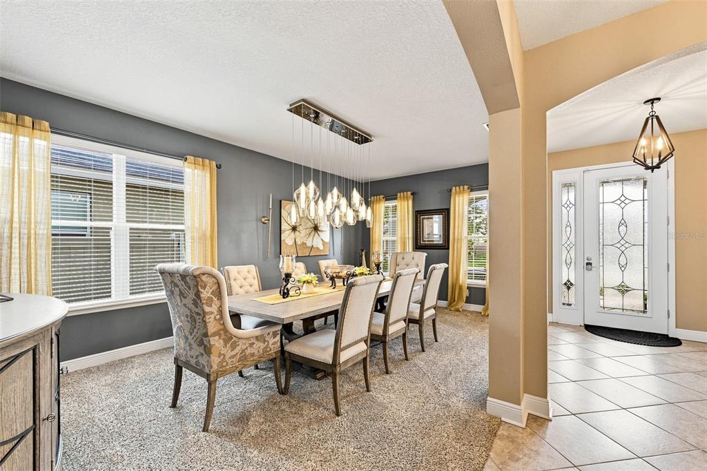 A dining room with a long table, upholstered chairs, and a modern multi-light pendant fixture — 11156 SPRING POINT CIRCLE, RIVERVIEW, FL
