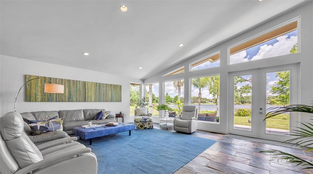 A modern bedroom features a bed, dresser, large windows, and a glass door overlooking water — 1841 LAKE SPIER DRIVE, WINTER PARK, FL