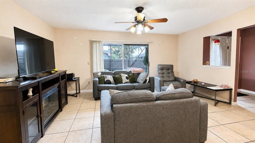 A living room features tile flooring, a ceiling fan, a sofa, and a television console — 3914 NW CINNAMON TREE CIRCLE, JENSEN BEACH, FL