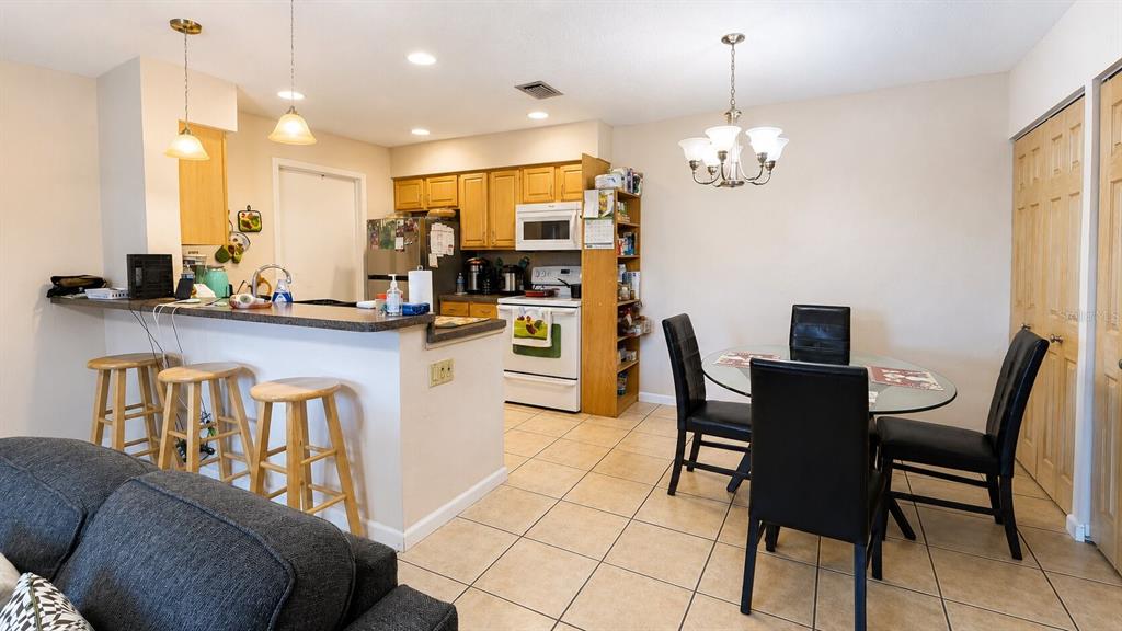 A kitchen with a breakfast bar and dining area featuring tile floors and wooden cabinets — 3914 NW CINNAMON TREE CIRCLE, JENSEN BEACH, FL