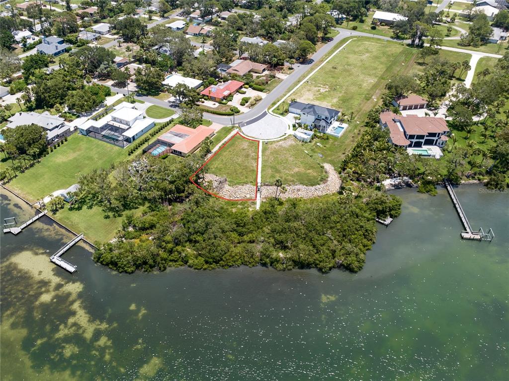An aerial view shows a vacant waterfront lot outlined in red at the end of a cul-de-sac — 1461 BAYSHORE ROAD, NOKOMIS, FL