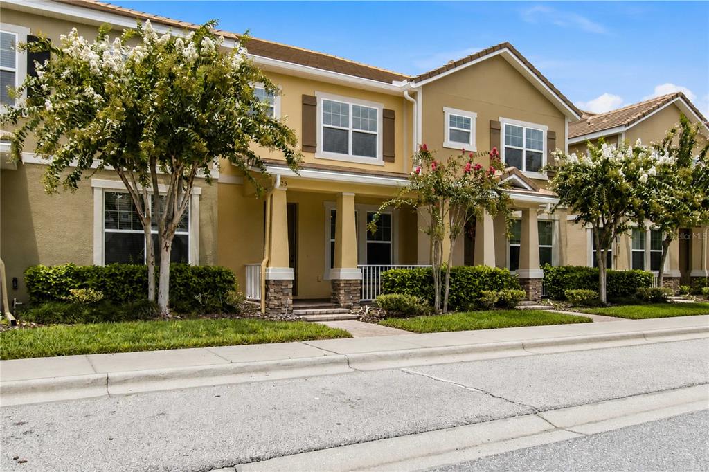 A two-story townhouse with a tan stucco exterior, stone-based columns, and a paved walkway — 11425 BROWNSTONE STREET, WINDERMERE, FL