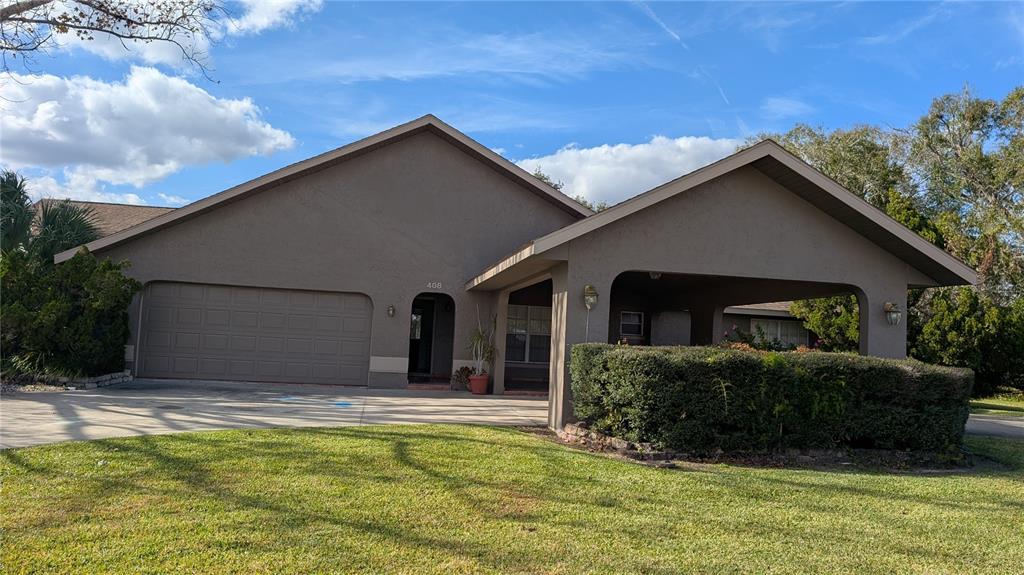 A single-story house features a two-car garage, a covered carport, and a large front lawn — 408 LEXINGTON DRIVE, SEBRING, FL