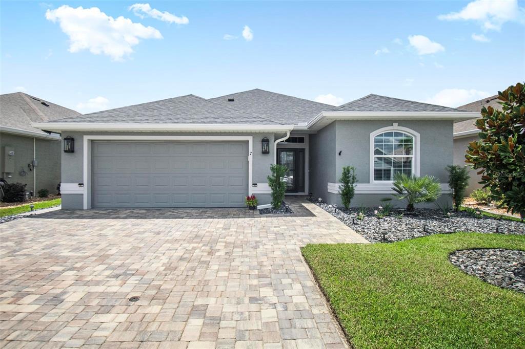 A single-story gray house with a paver driveway, two-car garage, and a landscaped front yard — 7 TIDEWAY TRAIL, PALM COAST, FL