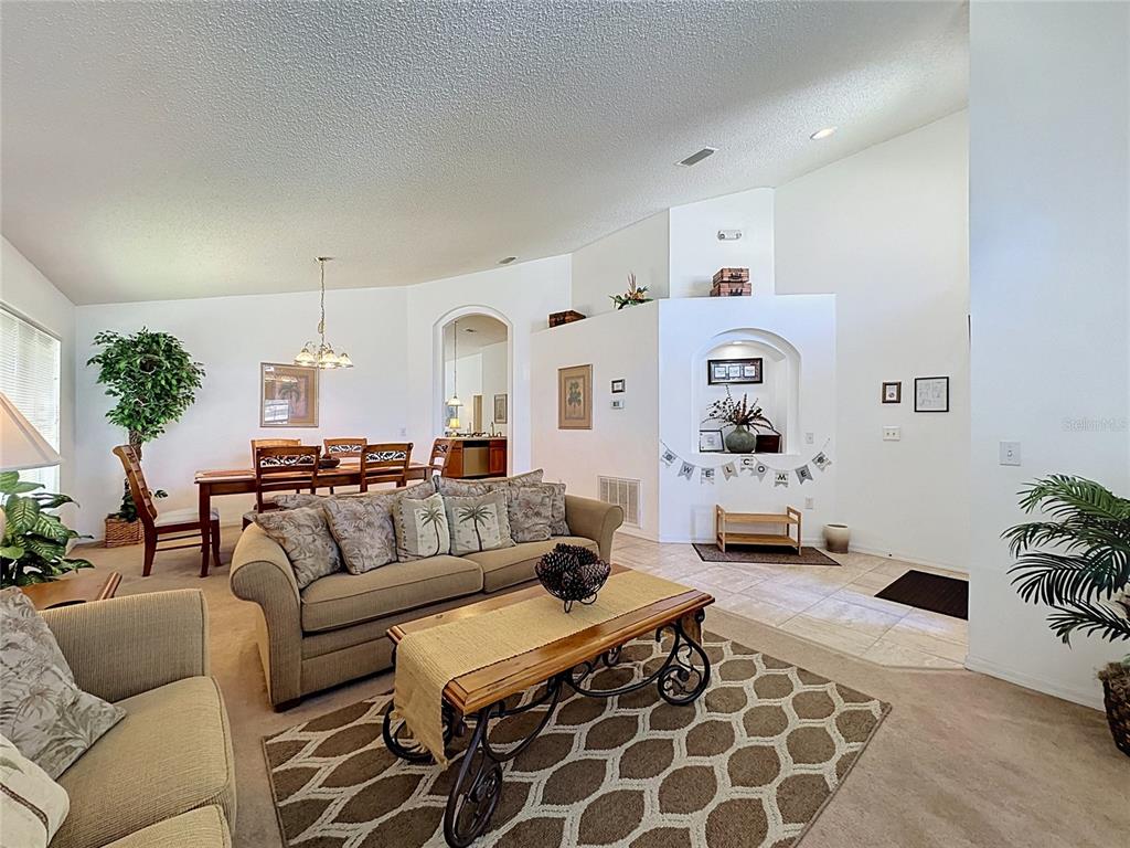A living room with a beige sofa, coffee table, and an arched entryway to the dining — 2817 KOKOMO LOOP, HAINES CITY, FL