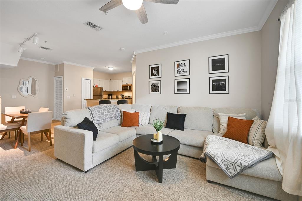 A living room with a beige sectional sofa, a round coffee table, and an adjacent dining area — 2637 LEGACY VILLAS DRIVE UNIT 2637, MAITLAND, FL