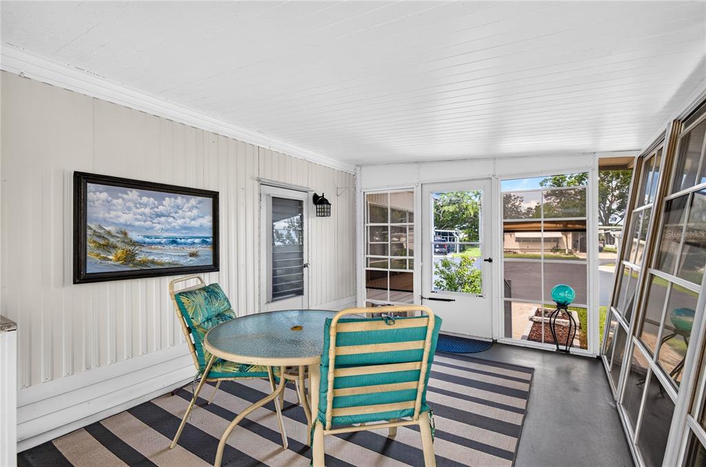 A screened-in porch features a glass-top table, two chairs, and a striped area rug — 9900 ULMERTON ROAD UNIT 28, LARGO, FL