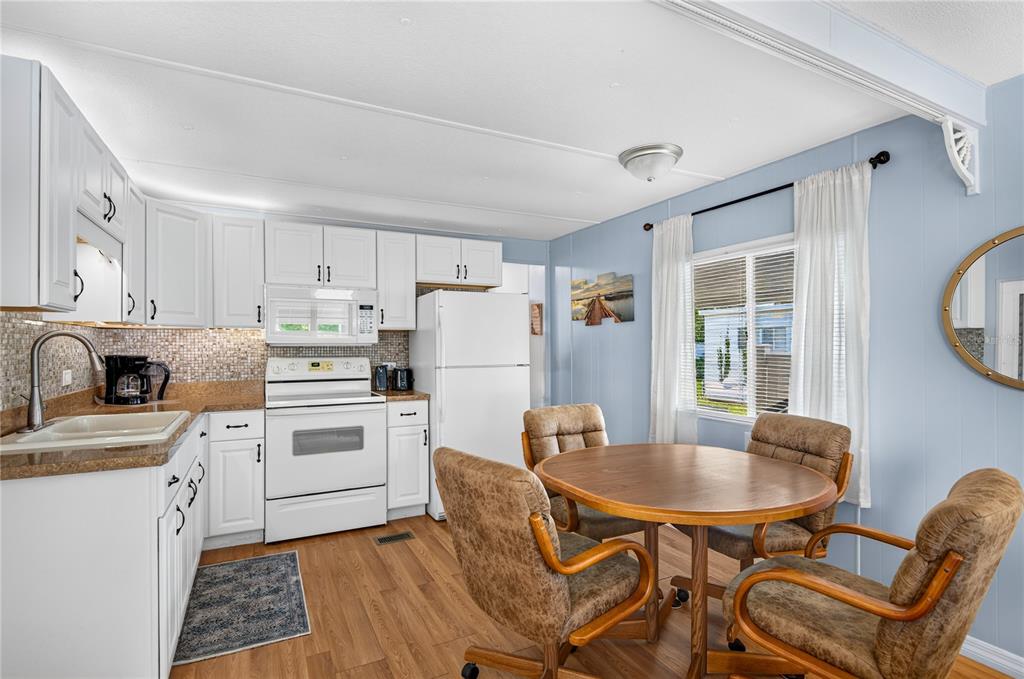 A kitchen with white cabinets, a white stove, and a round wooden dining table — 9900 ULMERTON ROAD UNIT 28, LARGO, FL