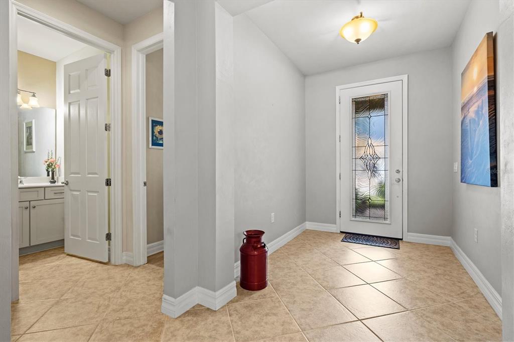 An entryway features a tiled floor, a white front door with decorative glass, and wall art — 19556 PETRINO STREET, VENICE, FL
