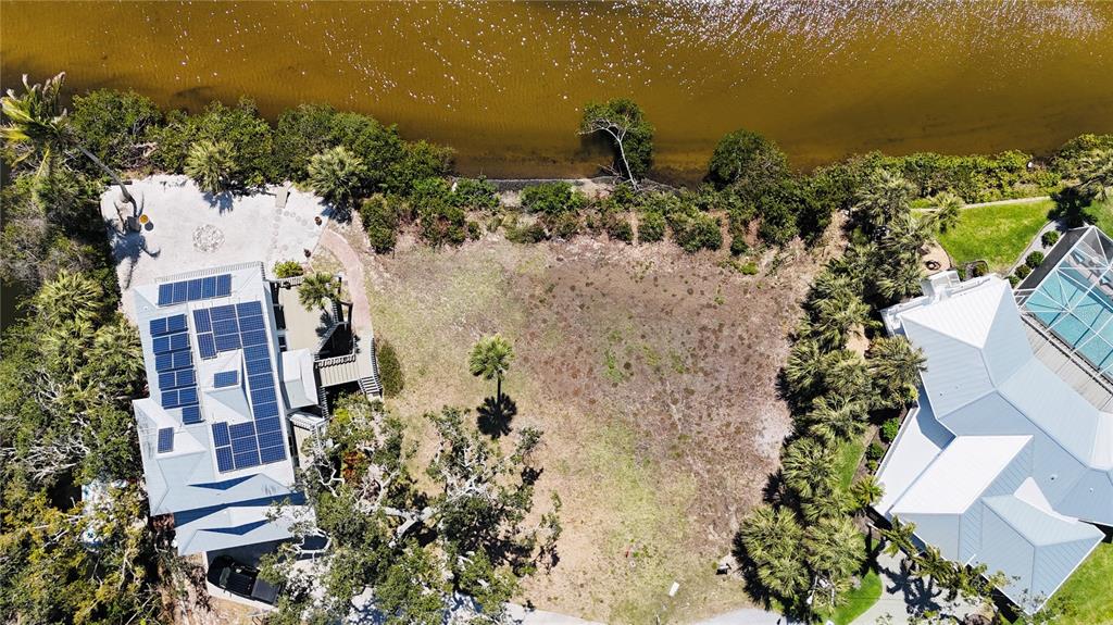 An aerial view shows a vacant lot situated between two houses along a waterfront — 808 SUNCREST DRIVE, NOKOMIS, FL