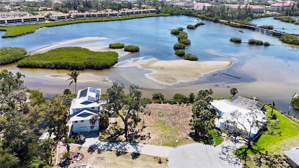 An aerial view shows two houses separated by a vacant lot near a tidal waterway — 808 SUNCREST DRIVE, NOKOMIS, FL