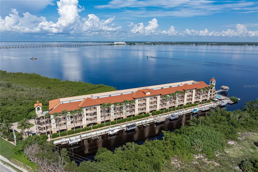 An aerial view of a multi-story waterfront condominium building with an attached boat dock — 900 E MARION AVENUE UNIT 1203, PUNTA GORDA, FL