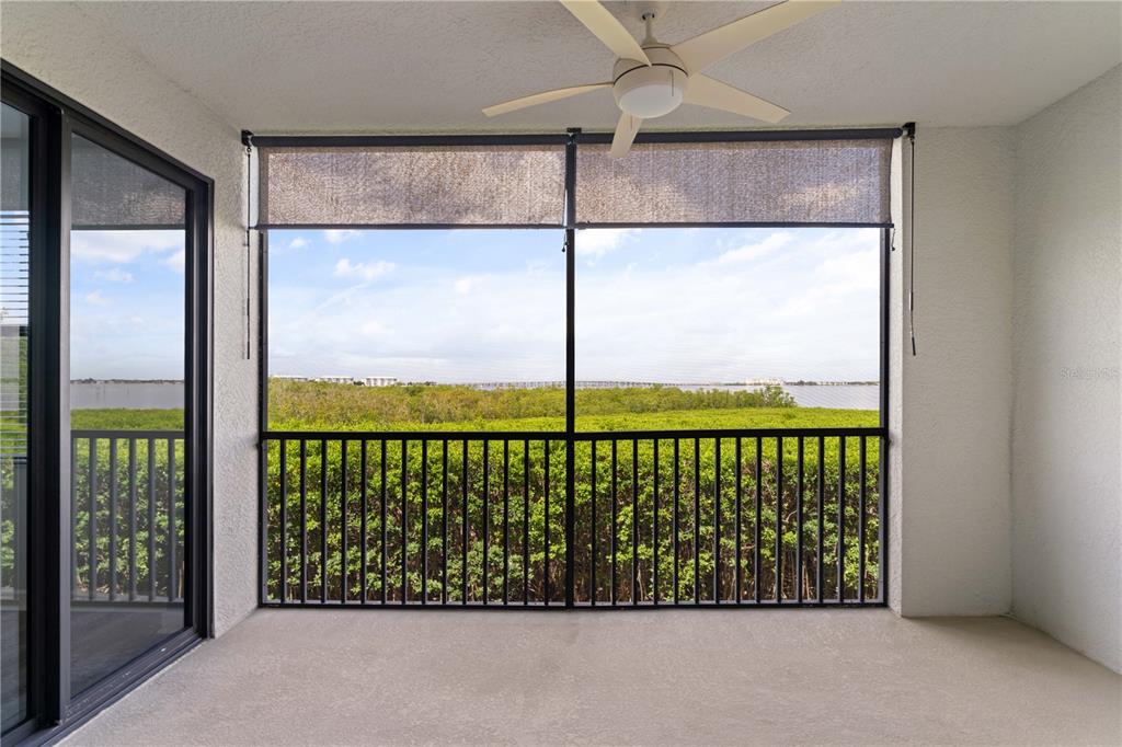A screened-in balcony features a ceiling fan, black railings, and a view of the water — 900 E MARION AVENUE UNIT 1203, PUNTA GORDA, FL