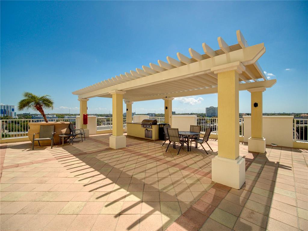 A rooftop terrace features a pergola, outdoor kitchen, dining set, and lounge chairs — 628 CLEVELAND STREET UNIT 1314, CLEARWATER, FL