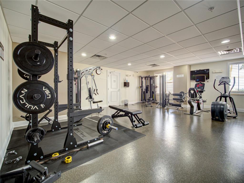 A gym room features a squat rack, weight bench, exercise machines, and a drop ceiling — 628 CLEVELAND STREET UNIT 1314, CLEARWATER, FL