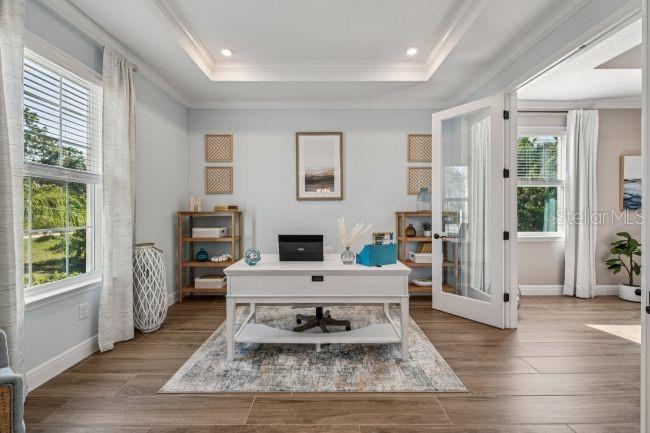 A home office features a white desk, wood-look tile floors, and glass-paneled double doors — 52 CACTUS STREET E, HOMOSASSA, FL