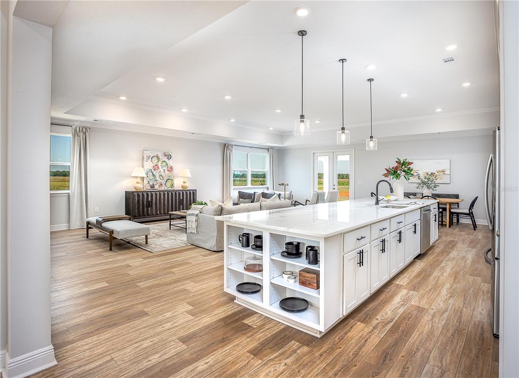 An open-concept kitchen and living area features a large white island, wood-look flooring, and recessed lighting — 52 CACTUS STREET E, HOMOSASSA, FL